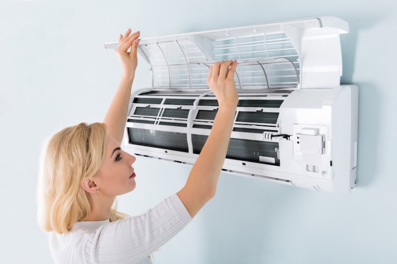 A Young Woman Cleaning Air Conditioning System At Home.