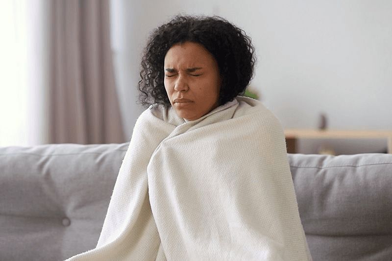 Black women shivering with blanket wrapped around her